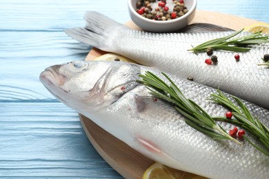 Photo of Fresh raw seabass with spices on blue wooden table, closeup. Fish and seafood delicacies