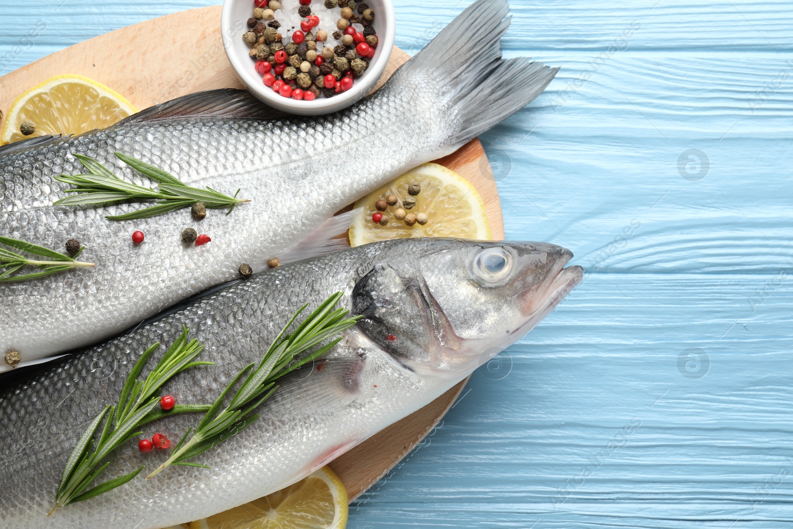 Fresh raw seabass with spices on blue wooden table, top view. Fish and seafood delicacies Photo of Fresh raw seabass with spices on blue wooden table, top view. Fish and seafood delicacies