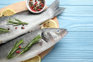 Photo of Fresh raw seabass with spices on blue wooden table, top view. Fish and seafood delicacies