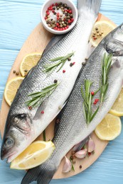 Photo of Fresh raw seabass with spices on blue wooden table, top view. Fish and seafood delicacies
