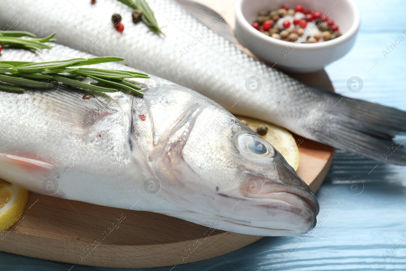 Fresh raw seabass with spices on blue wooden table, closeup. Fish and seafood delicacies Photo of Fresh raw seabass with spices on blue wooden table, closeup. Fish and seafood delicacies