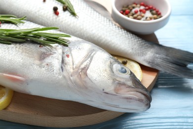 Photo of Fresh raw seabass with spices on blue wooden table, closeup. Fish and seafood delicacies