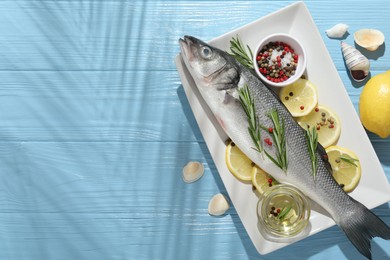 Photo of Fresh raw seabass fish with spices on blue wooden table, flat lay and space for text. Seafood delicacies