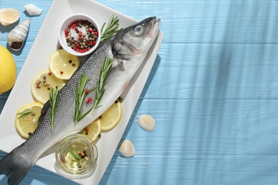 Photo of Fresh raw seabass fish with spices on blue wooden table, flat lay and space for text. Seafood delicacies