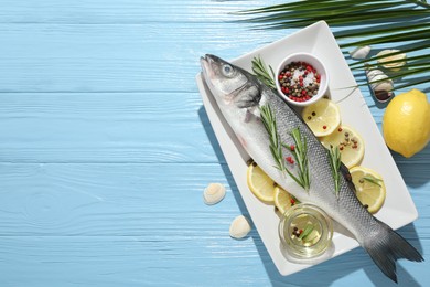 Photo of Fresh raw seabass fish with spices on blue wooden table, flat lay and space for text. Seafood delicacies