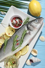 Photo of Fresh raw seabass with spices on blue wooden table, flat lay. Fish and seafood delicacies
