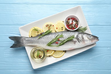 Photo of Fresh raw seabass with spices on blue wooden table, top view. Fish and seafood delicacies