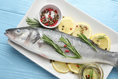 Photo of Fresh raw seabass with spices on blue wooden table, top view. Fish and seafood delicacies