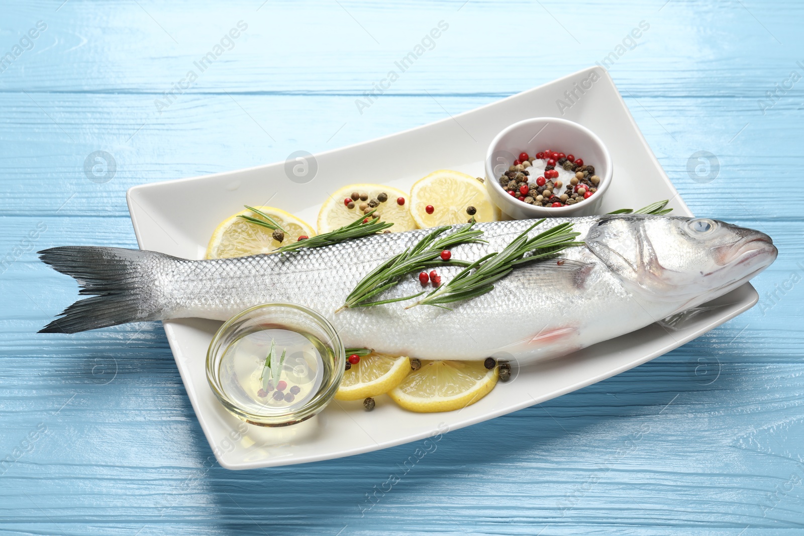 Fresh raw seabass with spices on blue wooden table. Fish and seafood delicacies Photo of Fresh raw seabass with spices on blue wooden table. Fish and seafood delicacies