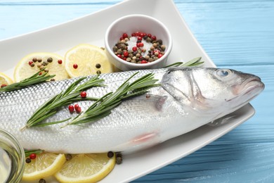 Photo of Fresh raw seabass with spices on blue wooden table, closeup. Fish and seafood delicacies