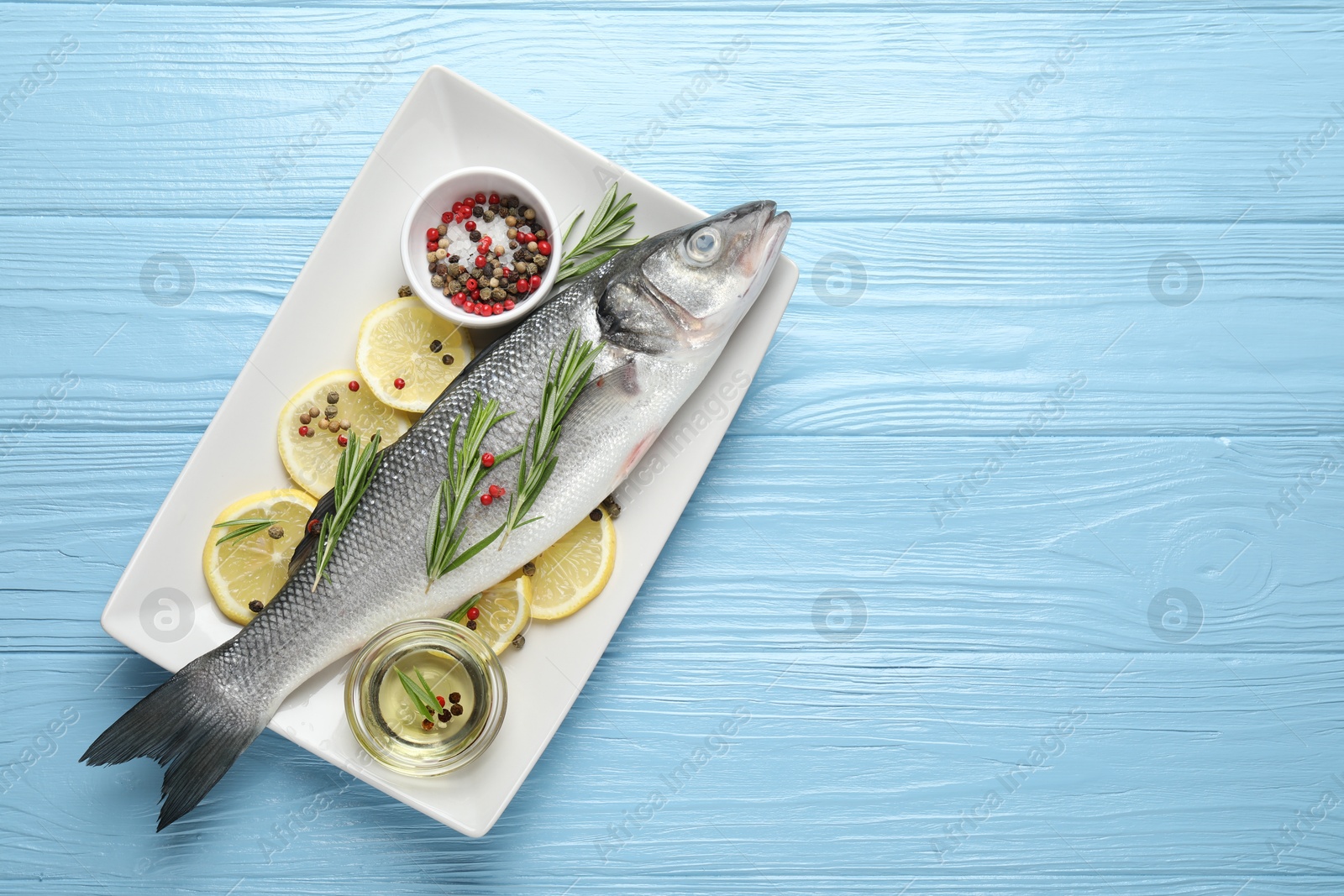 Fresh raw seabass fish with spices on blue wooden table, top view and space for text. Seafood delicacies Photo of Fresh raw seabass fish with spices on blue wooden table, top view and space for text. Seafood delicacies