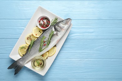 Photo of Fresh raw seabass fish with spices on blue wooden table, top view and space for text. Seafood delicacies