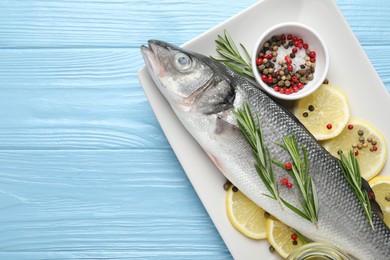 Photo of Fresh raw seabass fish with spices on blue wooden table, top view and space for text. Seafood delicacies