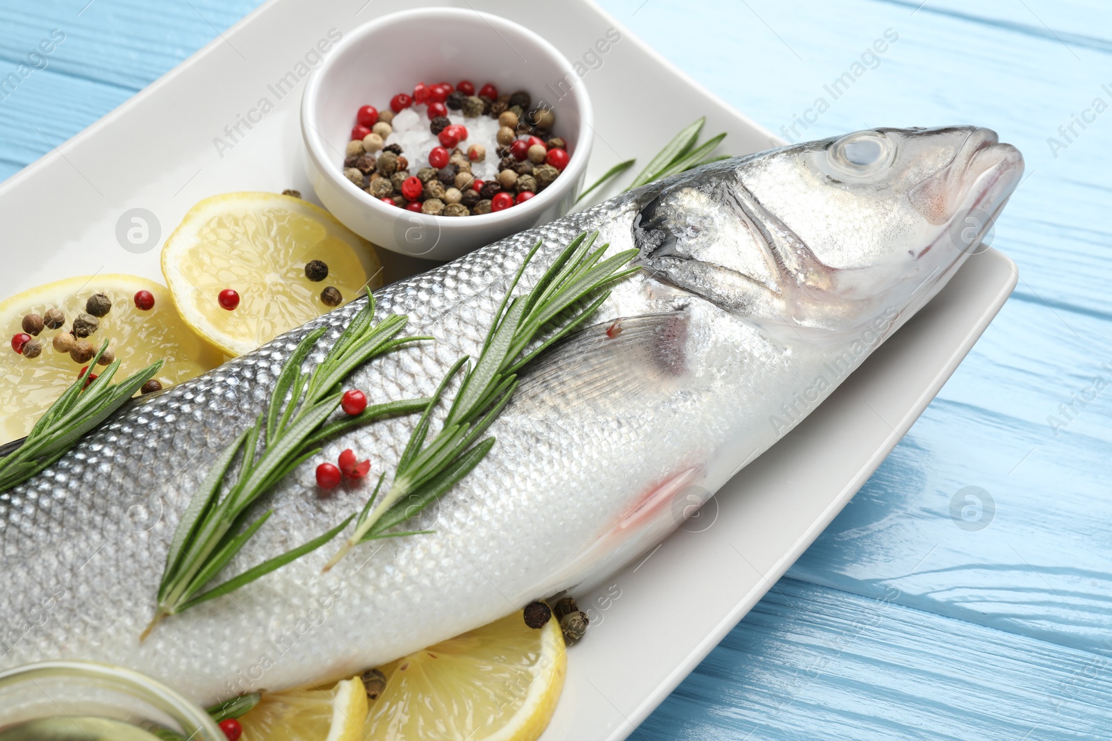 Fresh raw seabass with spices on blue wooden table, closeup. Fish and seafood delicacies Photo of Fresh raw seabass with spices on blue wooden table, closeup. Fish and seafood delicacies