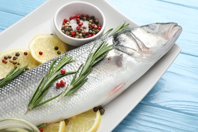 Photo of Fresh raw seabass with spices on blue wooden table, closeup. Fish and seafood delicacies