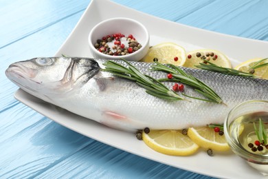 Photo of Fresh raw seabass with spices on blue wooden table, closeup. Fish and seafood delicacies