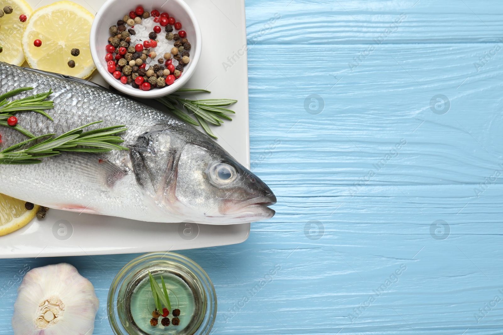 Fresh raw seabass fish with spices on blue wooden table, flat lay and space for text. Seafood delicacies Photo of Fresh raw seabass fish with spices on blue wooden table, flat lay and space for text. Seafood delicacies