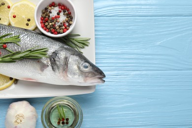 Photo of Fresh raw seabass fish with spices on blue wooden table, flat lay and space for text. Seafood delicacies