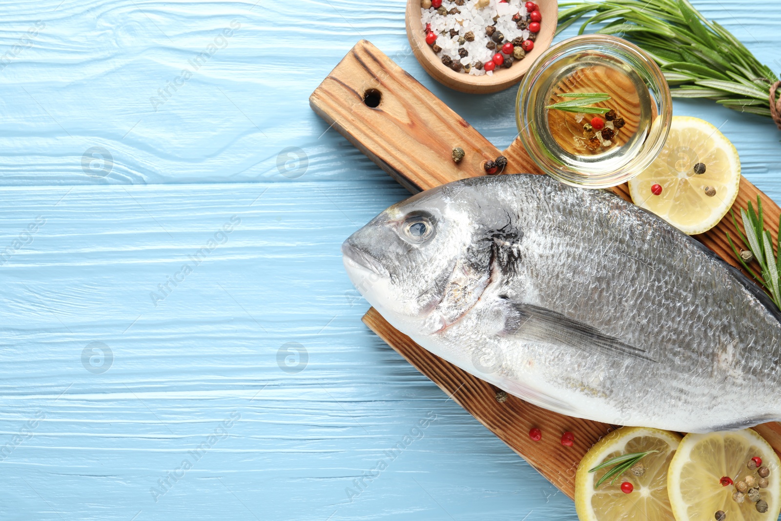 Fresh raw dourade fish with spices on blue wooden table, flat lay and space for text. Seafood delicacies Photo of Fresh raw dourade fish with spices on blue wooden table, flat lay and space for text. Seafood delicacies