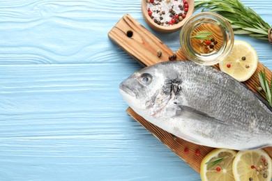 Photo of Fresh raw dourade fish with spices on blue wooden table, flat lay and space for text. Seafood delicacies