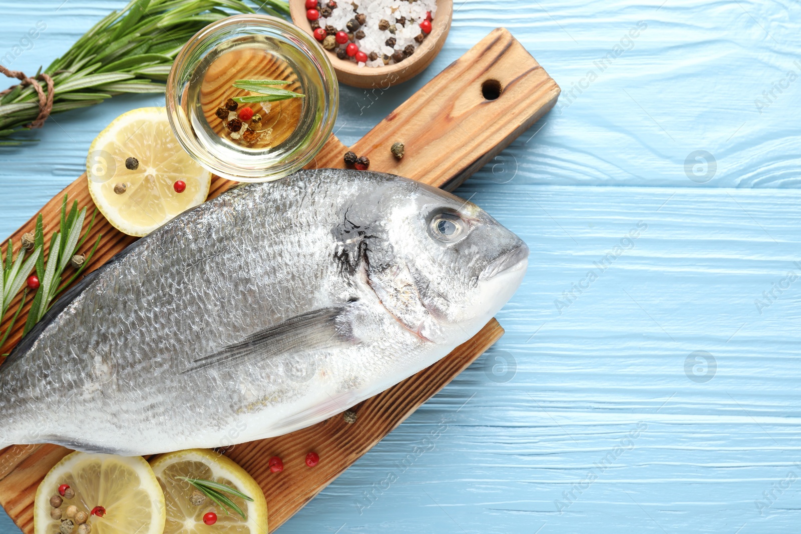 Fresh raw dourade fish with spices on blue wooden table, flat lay and space for text. Seafood delicacies Photo of Fresh raw dourade fish with spices on blue wooden table, flat lay and space for text. Seafood delicacies