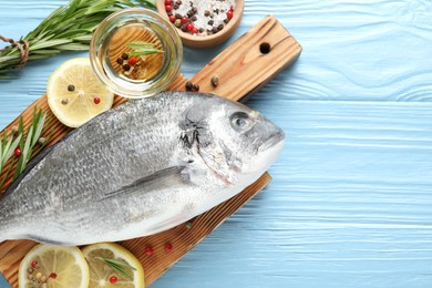 Photo of Fresh raw dourade fish with spices on blue wooden table, flat lay and space for text. Seafood delicacies