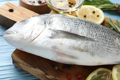 Photo of Fresh raw dourade with spices on blue wooden table, closeup. Fish and seafood delicacies