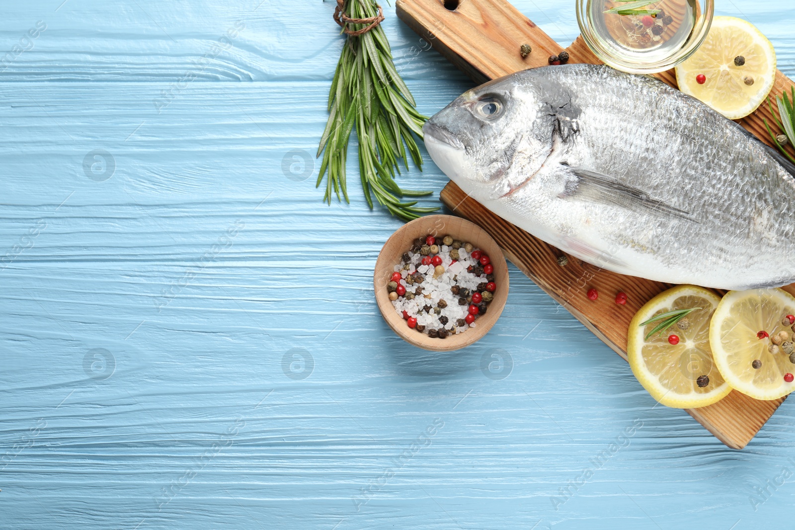 Fresh raw dourade fish with spices on blue wooden table, flat lay and space for text. Seafood delicacies Photo of Fresh raw dourade fish with spices on blue wooden table, flat lay and space for text. Seafood delicacies