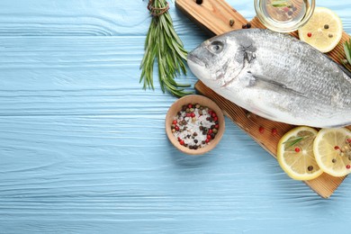 Photo of Fresh raw dourade fish with spices on blue wooden table, flat lay and space for text. Seafood delicacies