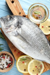 Photo of Fresh raw dourade with spices on blue wooden table, closeup. Fish and seafood delicacies