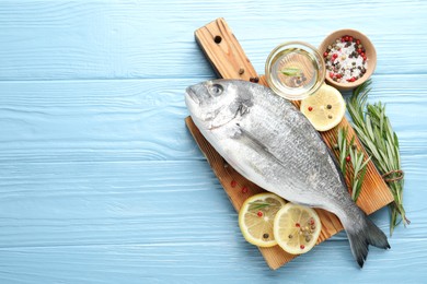 Photo of Fresh raw dourade fish with spices on blue wooden table, flat lay and space for text. Seafood delicacies
