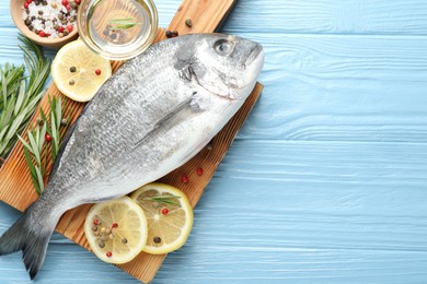 Photo of Fresh raw dourade fish with spices on blue wooden table, flat lay and space for text. Seafood delicacies