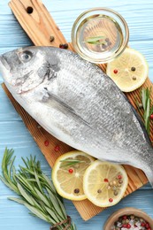 Photo of Fresh raw dourade with spices on blue wooden table, flat lay. Fish and seafood delicacies