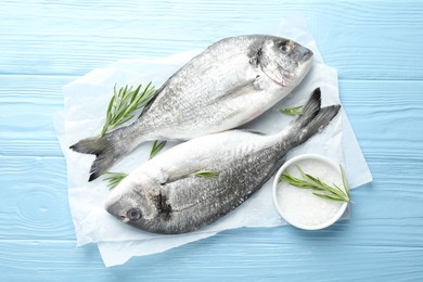 Photo of Fresh raw dourade with spices on blue wooden table, top view. Fish and seafood delicacies