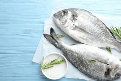 Photo of Fresh raw dourade fish with spices on blue wooden table, top view and space for text. Seafood delicacies