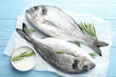 Photo of Fresh raw dourade with spices on blue wooden table, top view. Fish and seafood delicacies