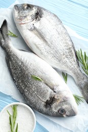 Photo of Fresh raw dourade with spices on blue wooden table, top view. Fish and seafood delicacies