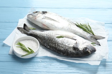 Photo of Fresh raw dourade with spices on blue wooden table. Fish and seafood delicacies