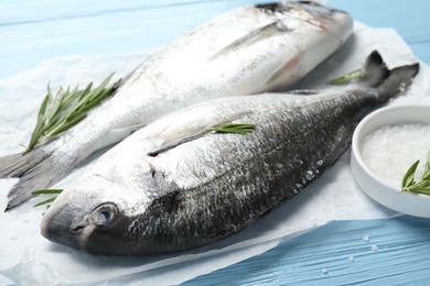 Photo of Fresh raw dourade with spices on blue wooden table, closeup. Fish and seafood delicacies