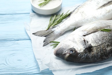 Photo of Fresh raw dourade with spices on blue wooden table, closeup. Fish and seafood delicacies