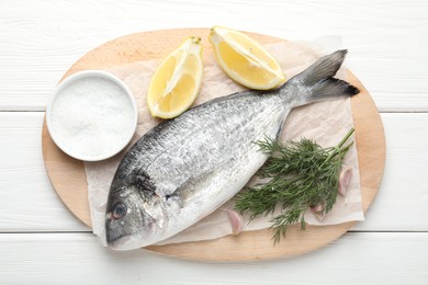 Photo of Fresh raw dourade with spices on white wooden table, top view. Fish and seafood delicacies