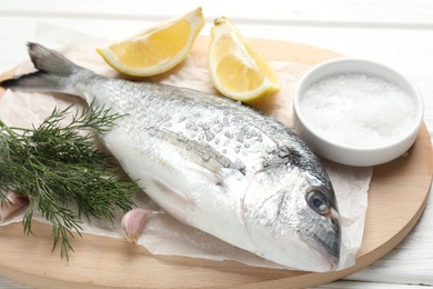 Photo of Fresh raw dourade with spices on white wooden table, closeup. Fish and seafood delicacies