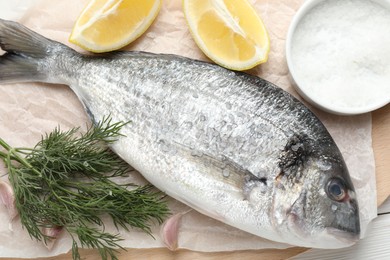 Photo of Fresh raw dourade with spices on white wooden table, closeup. Fish and seafood delicacies