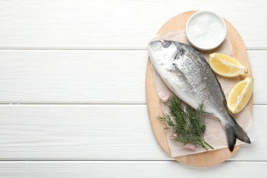 Photo of Fresh raw dourade fish with spices on white wooden table, top view and space for text. Seafood delicacies