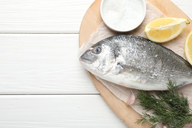 Photo of Fresh raw dourade fish with spices on white wooden table, top view and space for text. Seafood delicacies