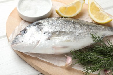 Photo of Fresh raw dourade with spices on white wooden table, closeup. Fish and seafood delicacies