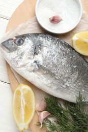 Photo of Fresh raw dourade with spices on white wooden table, closeup. Fish and seafood delicacies