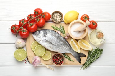 Photo of Fresh raw dourade with spices on white wooden table, flat lay. Fish and seafood delicacies