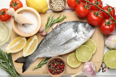 Photo of Fresh raw dourade with spices on white wooden table, flat lay. Fish and seafood delicacies