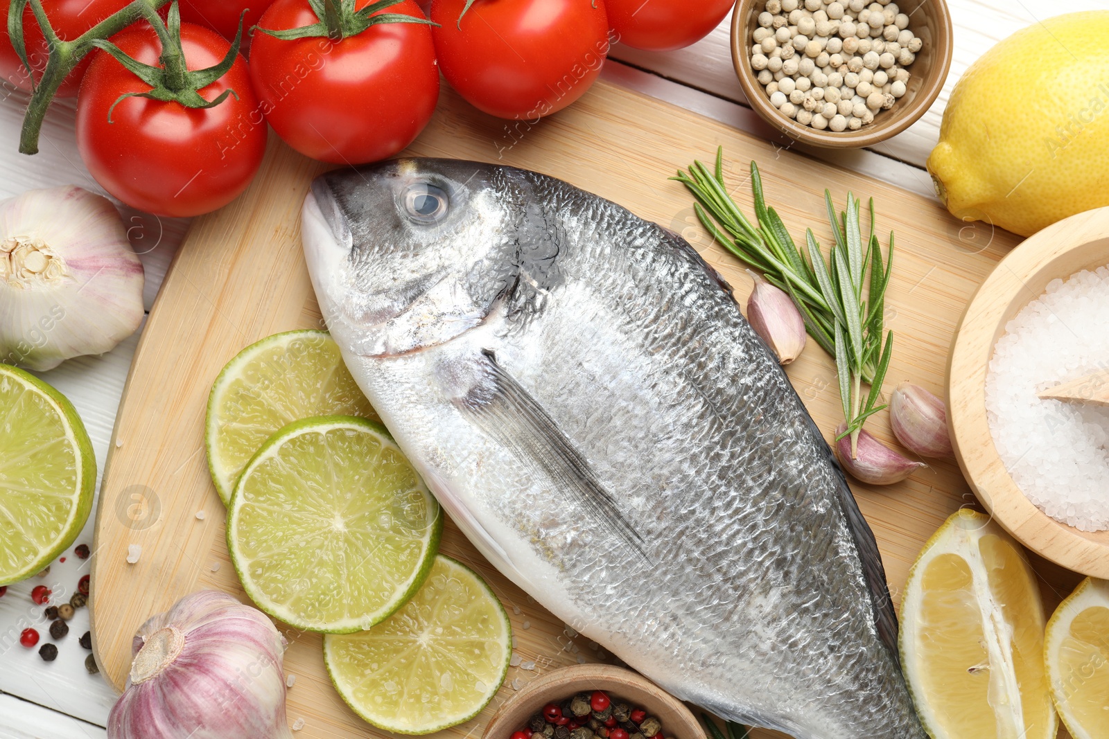 Fresh raw dourade with spices on white wooden table, flat lay. Fish and seafood delicacies Photo of Fresh raw dourade with spices on white wooden table, flat lay. Fish and seafood delicacies